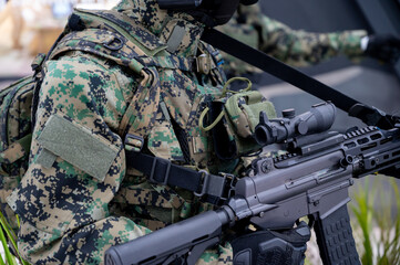 Modern soldier in digital camouflage holding tactical rifle during military operation