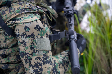 Modern soldier in digital camouflage holding tactical rifle during military operation