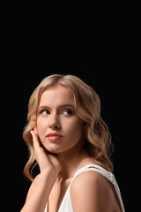 Naklejka premium Blonde young woman with curly hair on black background, closeup