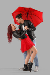 Young lovely couple with umbrella on grey background. Valentine's Day celebration