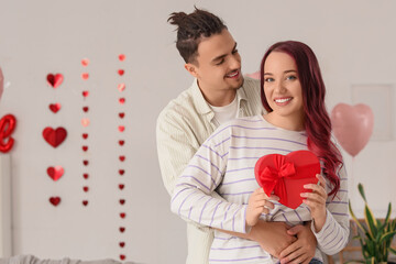 Young lovely couple with gift hugging at home. Valentine's Day celebration