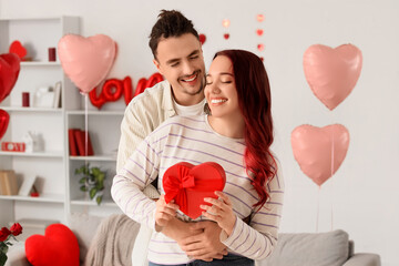 Young lovely couple with gift hugging at home. Valentine's Day celebration