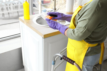 Woman with walker washing dishes in kitchen, closeup