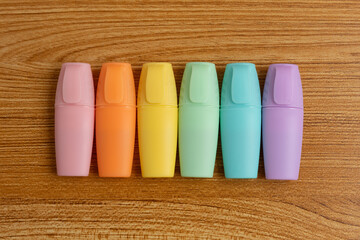 Pastel Highlighters Lined Up on Wooden Desk Background