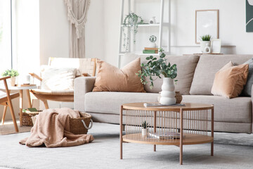 Interior of living room with sofa, armchair and artificial eucalyptus twigs in vase on coffee table © Pixel-Shot
