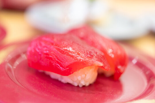 Assorted fresh sushi on colorful plates in a Japanese kaiten sushi restaurant
