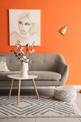 Interior of living room with cotton flowers in vase on table and sofa