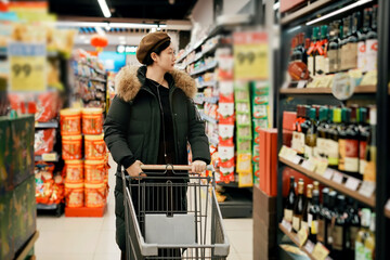 Woman Shopping with Cart in Supermarket Aisle