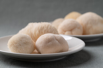 Fresh Lion's Mane mushroom,(Hericium erinaceus) on a white plate, known for nootropic benefits and medicinal properties © nungning20