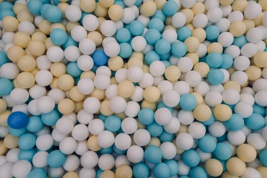 Plastic blue, white, and  yellow  balls at the playground. Background