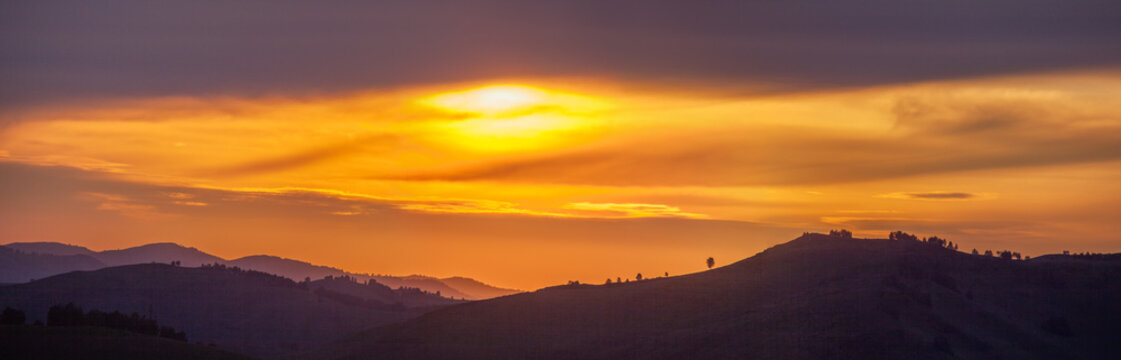 Picturesque sunset in the mountains, hills on the horizon, panoramic view