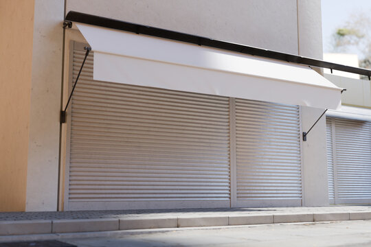Blank White Store Awning and Closed Roller Shutters