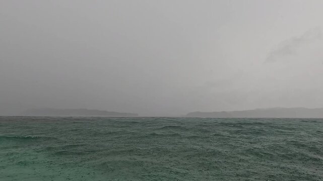 Heavy rains limit the visibility of the small islands in the distance.