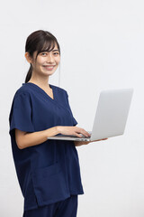 Smiling Young Woman in Navy Medical Scrubs Holding Laptop on White Background