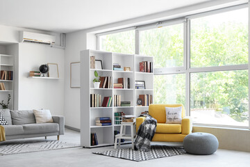 Interior of stylish living room with yellow armchair, pouf and bookshelf © Pixel-Shot