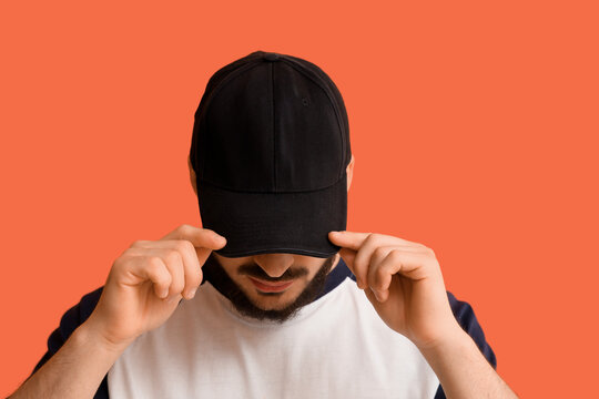 Handsome young man in stylish cap on orange background