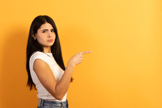 Young woman pointing right with skeptical expression