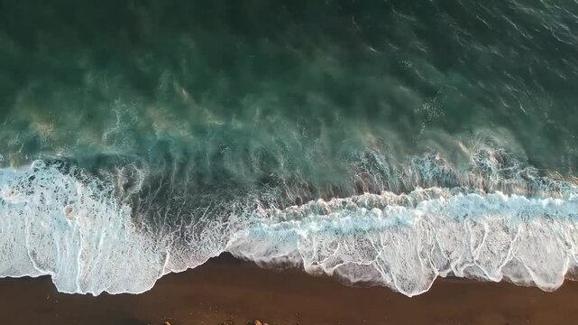This Ocean Sea Waves Drone Aerial View stock footage presents a breathtaking top-down perspective of ocean waves captured from a drone. The video reveals the rhythmic motion of the sea as waves roll,