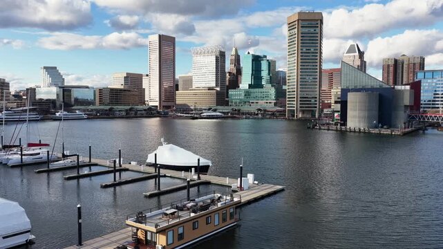 Aerial view of Baltimore&rsquo;s Inner Harbor with an American flag in foreground. Marina docks, calm harbor waters and downtown skyline under bright daytime sky. Wide shot.