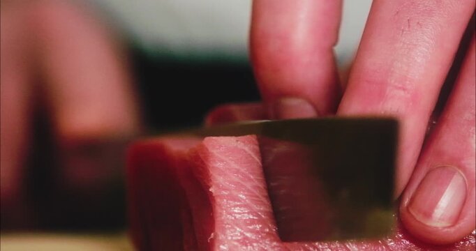 包丁で生のマグロの刺身を切り分ける寿司職人の手元　和食・日本料理のクローズアップ　魚介・海鮮料理　旅行・観光