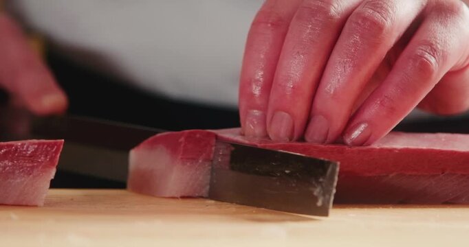 包丁で生のブリ・カンパチ・ハマチ魚の刺身を切り分ける寿司職人の手元　和食・日本料理のクローズアップ　魚介・海鮮料理　旅行・観光
