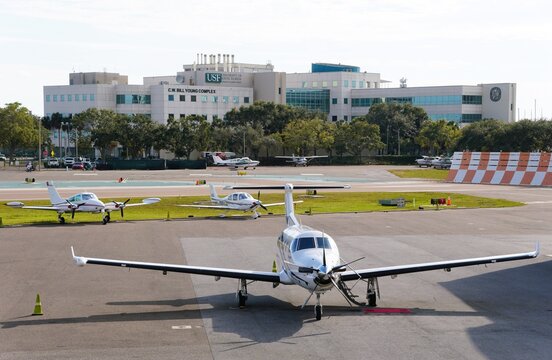 St Petersburg, Florida, U.S - Jan 2, 2026 - Several small private airplanes are parked on the tarmac at Albert Whitted Airport, with USF buildings in the background
