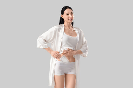 Young woman with applied medical patch after appendectomy surgery on grey background