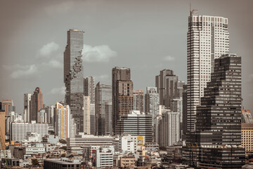 Fototapeta premium Bathed in the muted light of an overcast sky, Bangkok skyline reveals a striking dialogue between sleek modernism and weathered low-rise architecture. At the heart of this contemplative scene, the 'pi