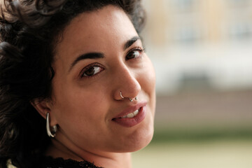Portrait of smiling young woman with nose piercing and curly hair