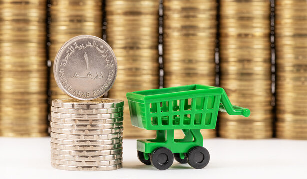 A 1 dirham coin of the United Arab Emirates against a background of stacks of coins on a white background