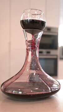 Red Wine Pouring Through Aerator Into Glass Decanter in Modern Kitchen
