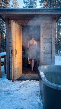 Woman in Towel doing alternating Hot and cold treatment in wellness spa. Sauna and cold plunge ice bath. . Wooden Sauna with Snowy Outdoor Setting and Black Hot Tub. Video made using Generative AI.