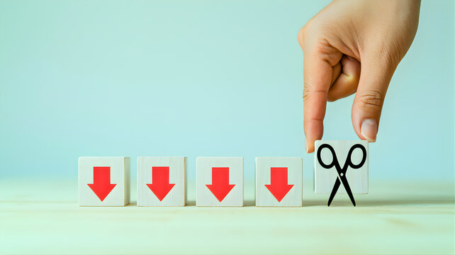 Strategic cost cutting and budget reduction represented by hand placing a scissor icon cube alongside a series of downward arrow blocks, symbolizing financial efficiency and loss prevention