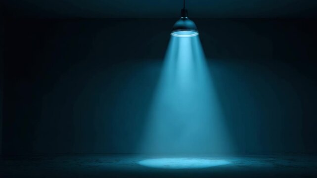 Blue spotlight illuminating empty concrete floor dark studio stage room with moody atmospheric haze and dramatic spotlighting, visible blue light beam and soft shadow highlighting texture