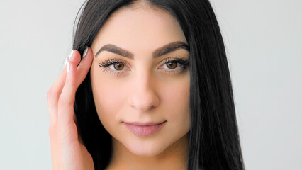 Naklejka premium Treatment beauty. Perfect skin. Young female touching soft face. Girl with long hair demonstrating natural makeup isolated on white.
