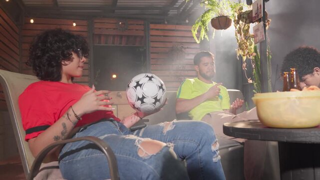 Friends discussing soccer game on a backyard patio at night