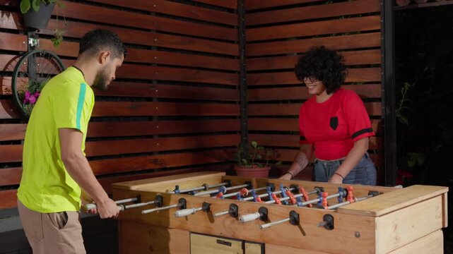 Friends enjoying playing a foosball game at night