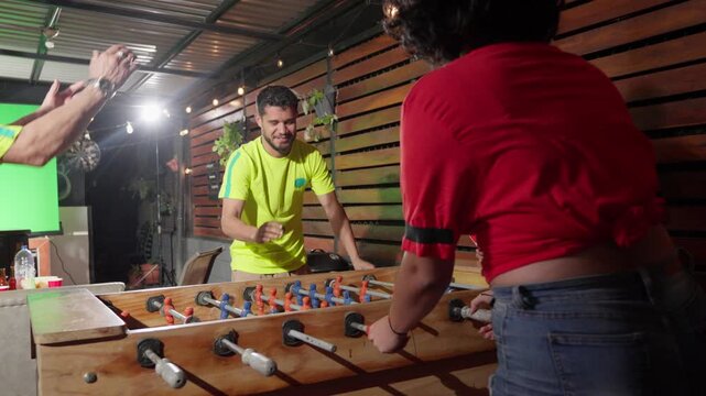 Friends playing foosball and celebrating a goal
