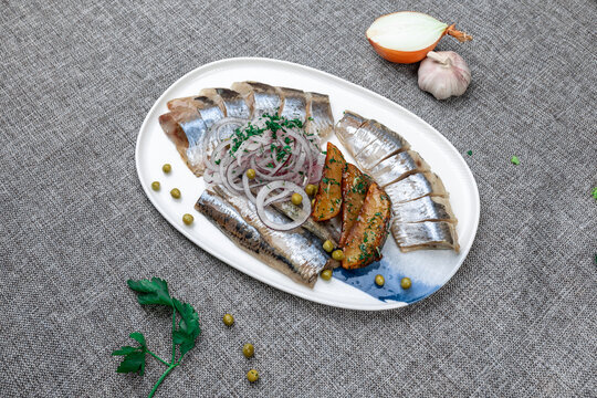 Traditional Russian cold appetizer platter (zakuski) with pickled herring, roasted potatoes, and red onions