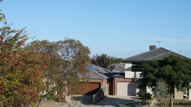 Modern suburban houses surrounded by trees in Australia. A quiet residential neighborhood with detached family homes. Suburban living scene in an established housing estate in Australia.