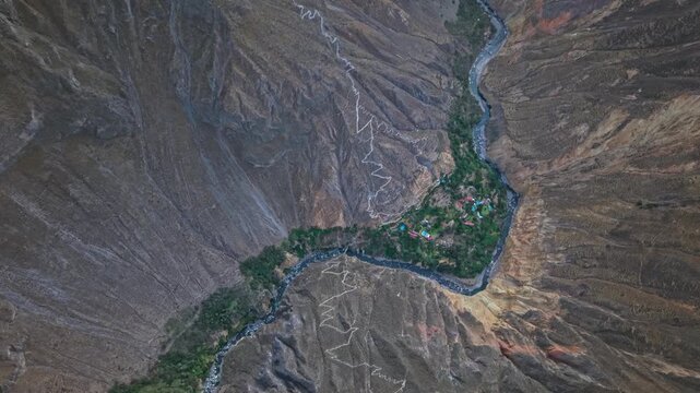 A high-altitude drone shot over the oasis shows the full width of Colca Canyon, stunning geology, visible hiking trails, the river, and accommodation capturing the canyon&rsquo;s epic scale.