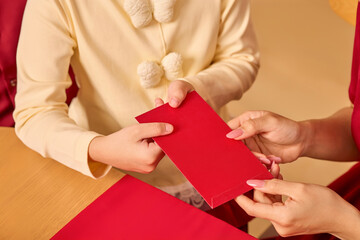 Obraz premium Close-up of hands passing a red envelope, symbolizing luck and tradition during an Asian New Year celebration