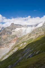 Obraz premium Expansive glacier cascades down rugged mountain slopes, with jagged peaks and a vivid blue sky overhead in the Glacier de Pre de Bar and Mont Dolent area.