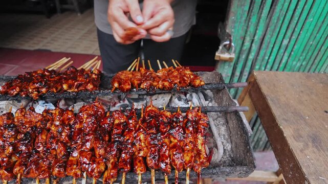 close-up of satay chicken grilled over charcoal