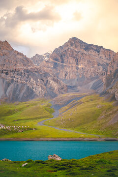 The front view of Tientang Hu lake, Xinjiang, China. There are many mountains behind. The sun was setting with soft light. There is a lush green lawn. The idea for Trekking wallpaper with copy space.
