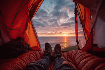 View from inside a tent at sunrise over the ocean with person's feet visible