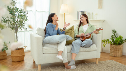 Obraz premium Happy Girls Enjoy Time Together on a Cozy Sofa While Playing Music in a Bright Living Room