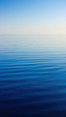 Obraz premium Calm ocean with gentle ripples under a clear sky.