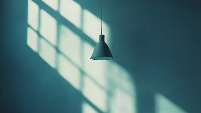 Hanging light fixture with minimalist design creating a subtle visual interest on a textured wall, illuminated by natural sunlight casting strong patterned shadows from a window grill