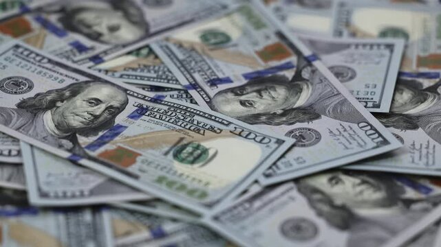 Close-up view of scattered US dollar banknotes featuring Benjamin Franklin, showcasing intricate details of currency design and texture on a flat surface